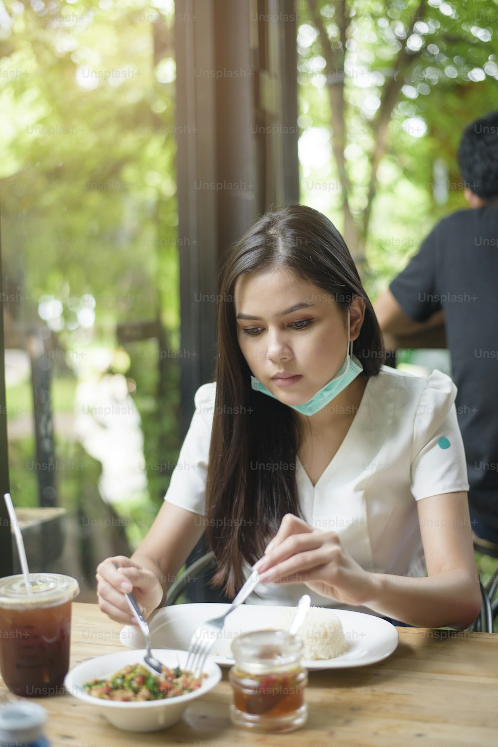 young woman with  face mask is having food in restaurant, New normal concept.