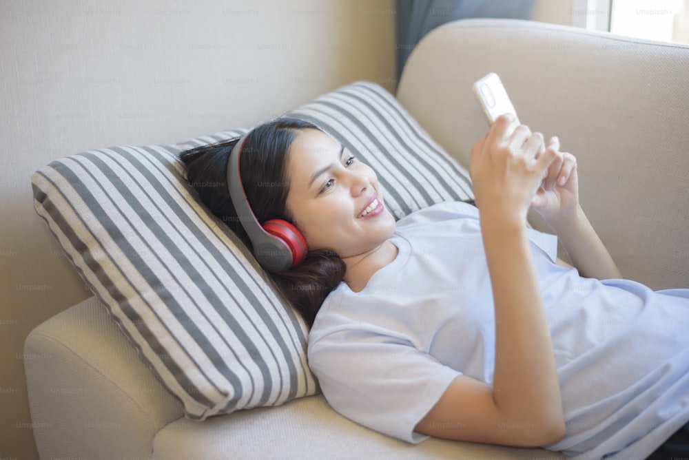Una giovane donna sta usando l'auricolare che si diverte con la musica in soggiorno, concetto di sicurezza domestica.