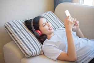 Una mujer joven está usando auriculares que disfrutan con música en la sala de estar, concepto de seguridad en el hogar.