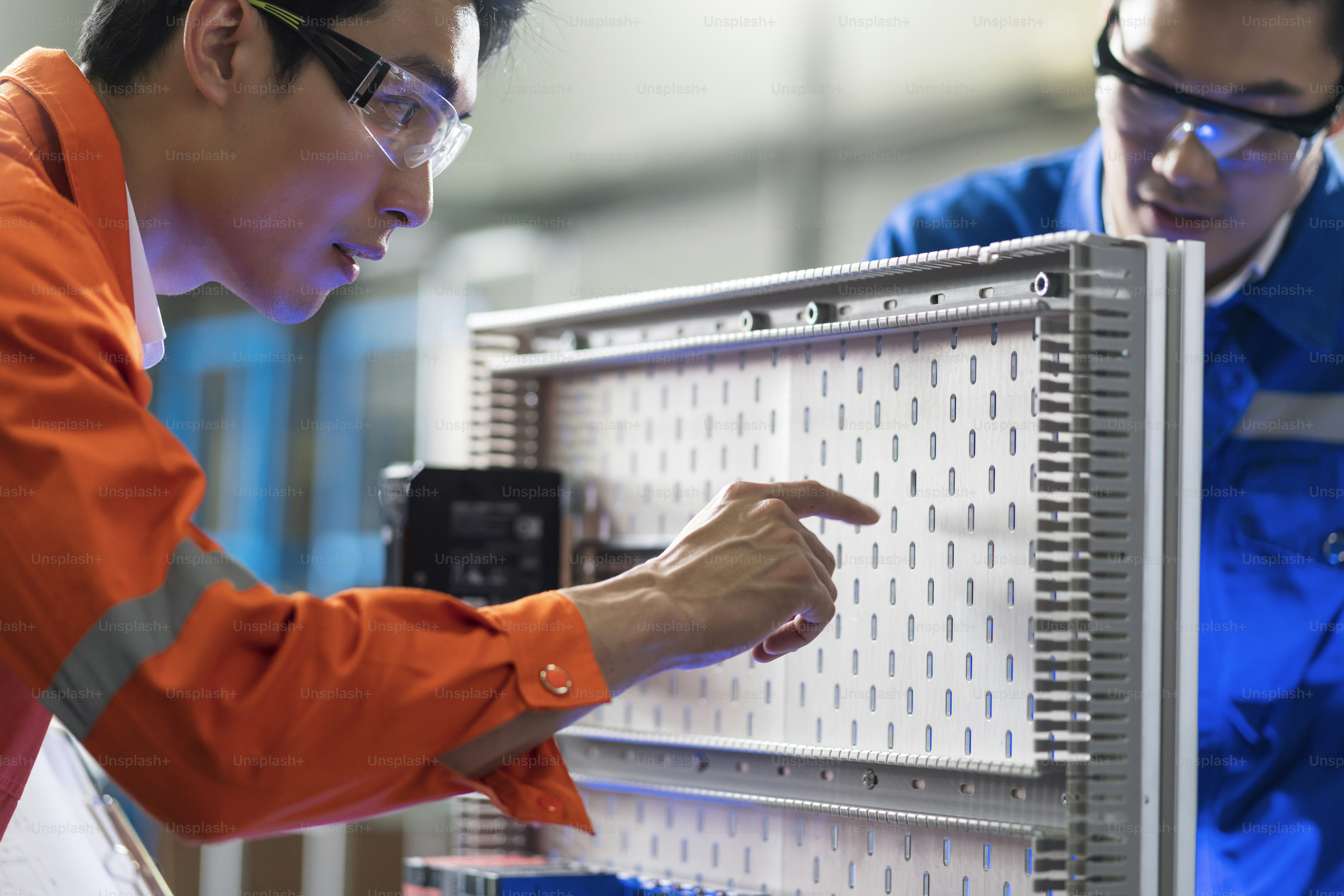 Male Asian engineer professional  having a discussion standing by the machine in the factory ,two asian coworker brainstorm explaining and solves the process curcuit mother board of the machine