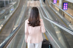 A business woman is wearing protective mask in International airport, travel under Covid-19 pandemic, safety travels, social distancing protocol, New normal travel concept.