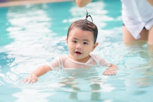 A Happy Asian mother and daughter are enjoy swimming in pool , lifestyle, parenthood, family concept .