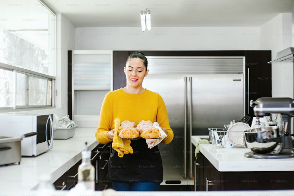 Mexican woman baking Pan de Muerto traditional bread from Mexico in Halloween
