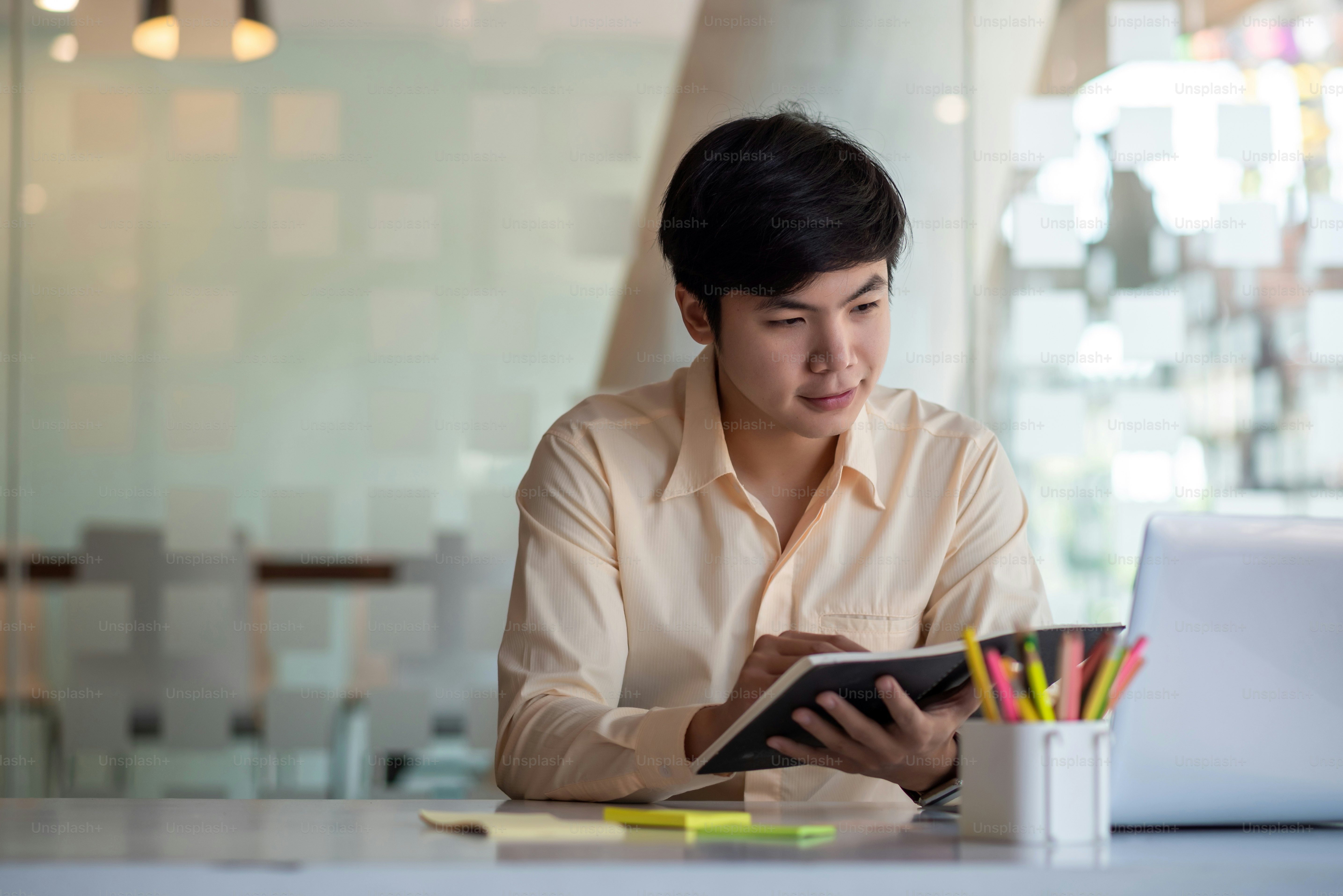 Pengusaha muda Asia duduk bekerja dengan komputer laptop di kantor modern.