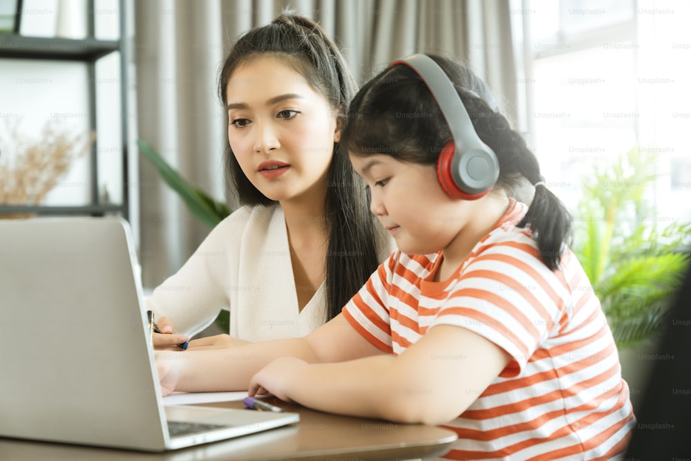asian mother enjoy teach and explain homework to child daughter for online study during homeschooling at home ,home quarantine, online learning new normal lifestyle