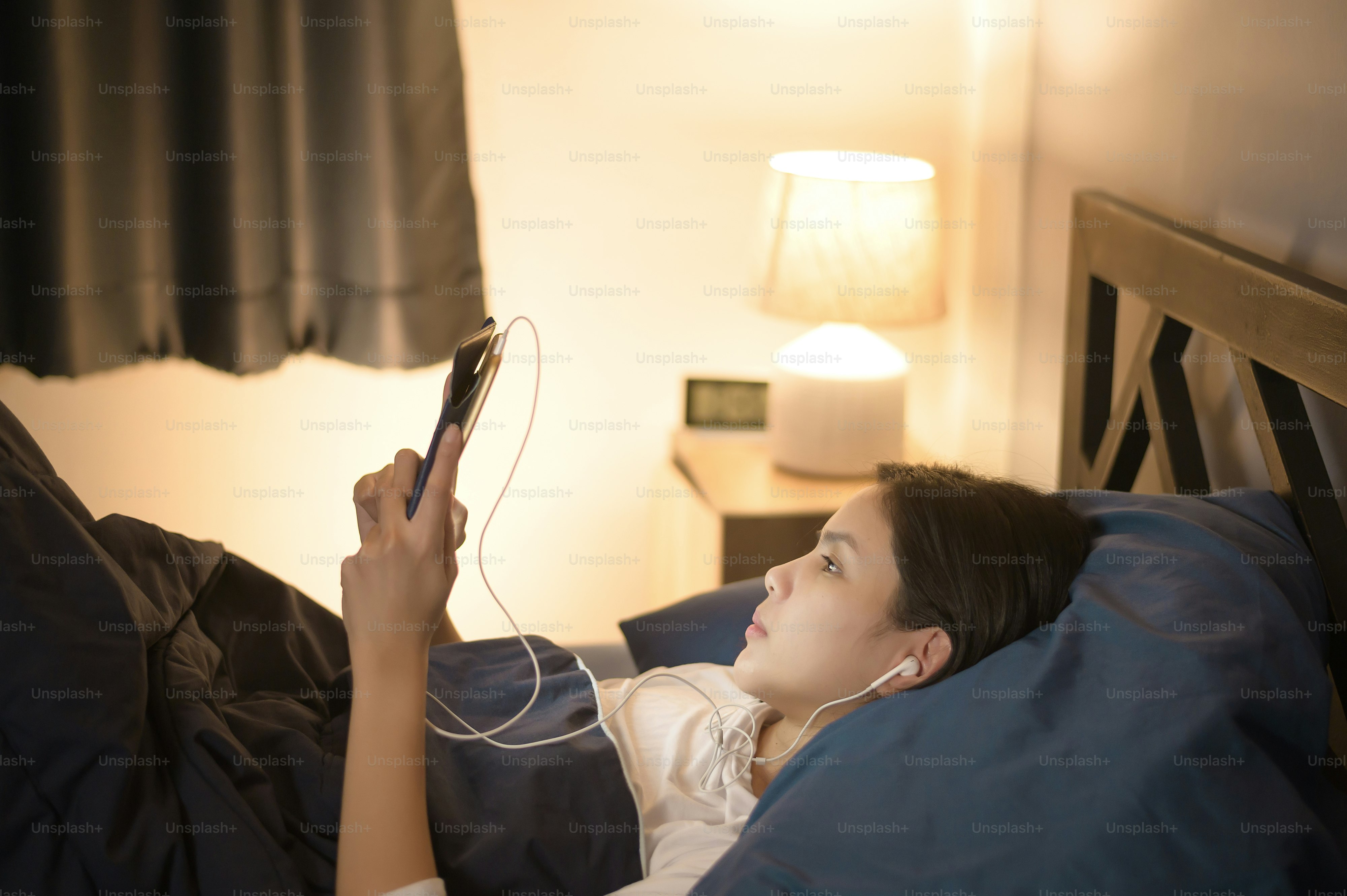A young woman is using tablet , watching movies or video call to her friends or family in her bedroom , night Light