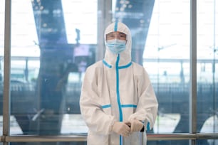 Ein asiatischer Mann trägt einen Psappenanzug im Flughafenaufzug, Sicherheitsreisen, Covid-19-Schutz, Social Distancing-Konzept.
