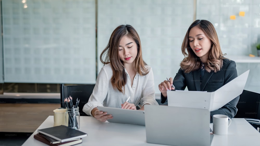 Two beautiful young asian businesswoman discussing document in office.