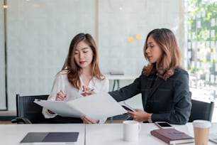 Two young asian businesswoman talking and working together at office.