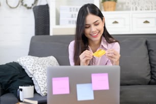 uma jovem mulher bonita está usando cartão de crédito para compras on-line no site da internet em casa, conceito de comércio eletrônico
