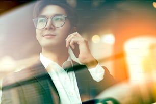 Kreativagentur Smart Glasses asiatischer Mann formelles Tuchgespräch mit Smartphone freiberuflich Arbeiten mit Laptop im Coworking Area Büroräume mit Frische mit unscharfem Bürohintergrund