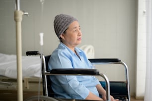 A depressed and hopeless Asian cancer patient woman wearing head scarf in hospital.