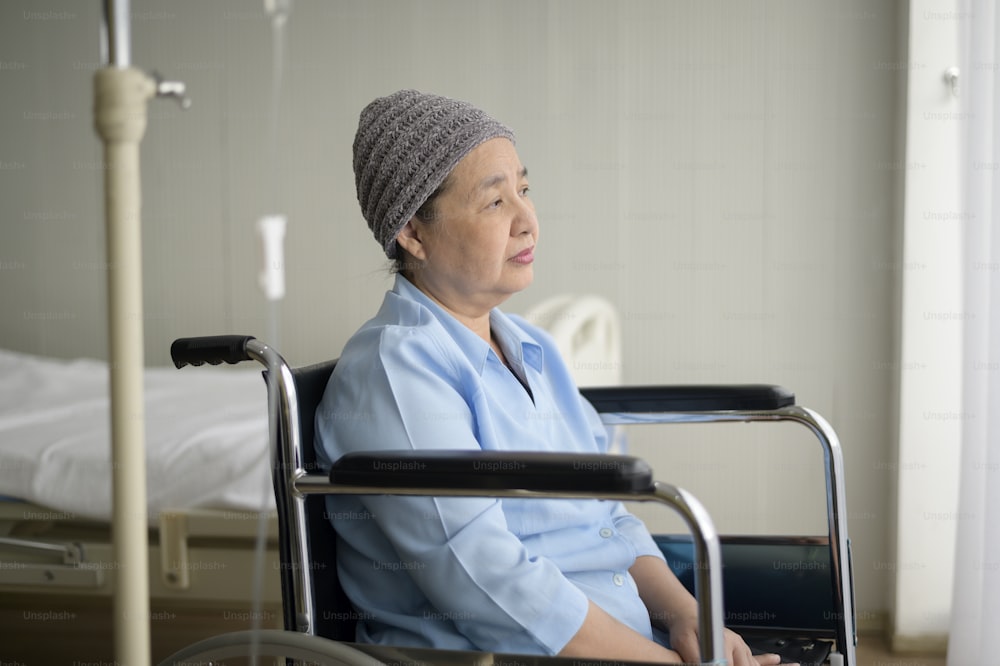 A depressed and hopeless Asian cancer patient woman wearing head scarf in hospital.