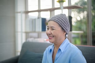 Partial front view of Thai woman in early 60s wearing knit hat due to hair loss during cancer treatment.