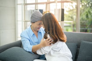 A cancer patient woman wearing head scarf hugging her supportive daughter indoors, health and insurance concept.