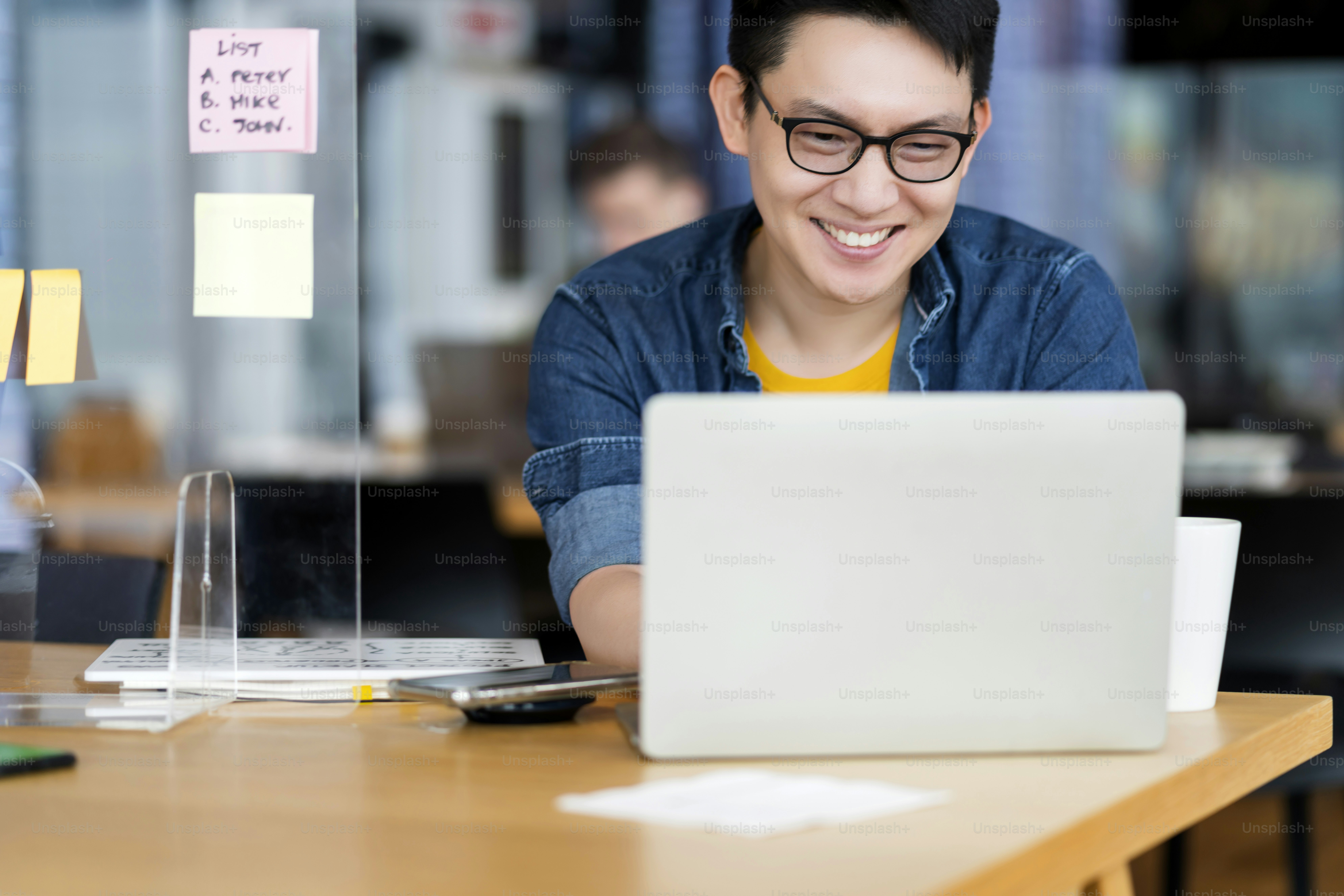 Photo of a person smiling while looking at their code, with a sticky note on the monitor that says “No complaining today – only solutions.”