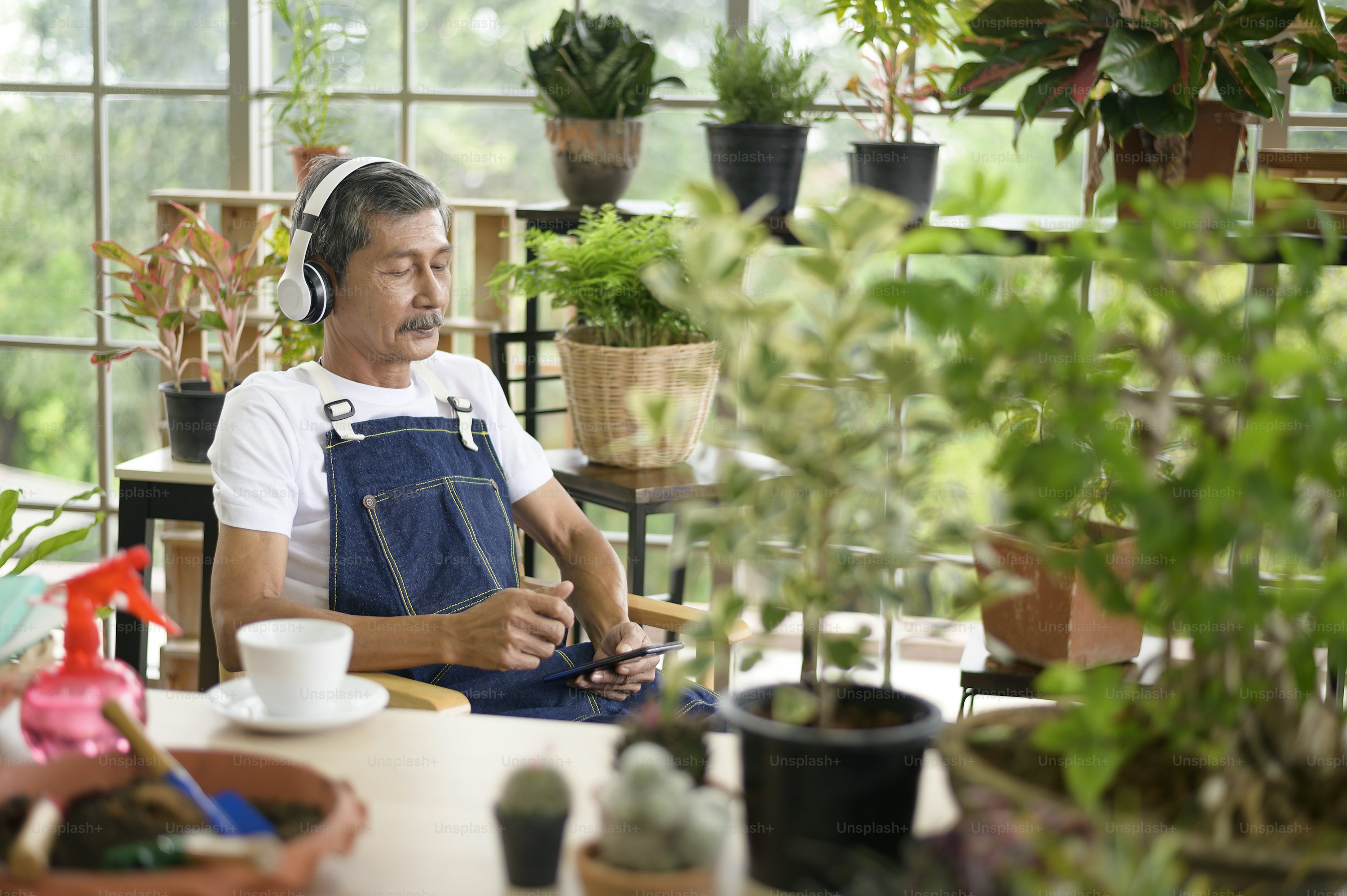 A happy senior asian retired man listening to music and enjoying leisure activity in garden at home.