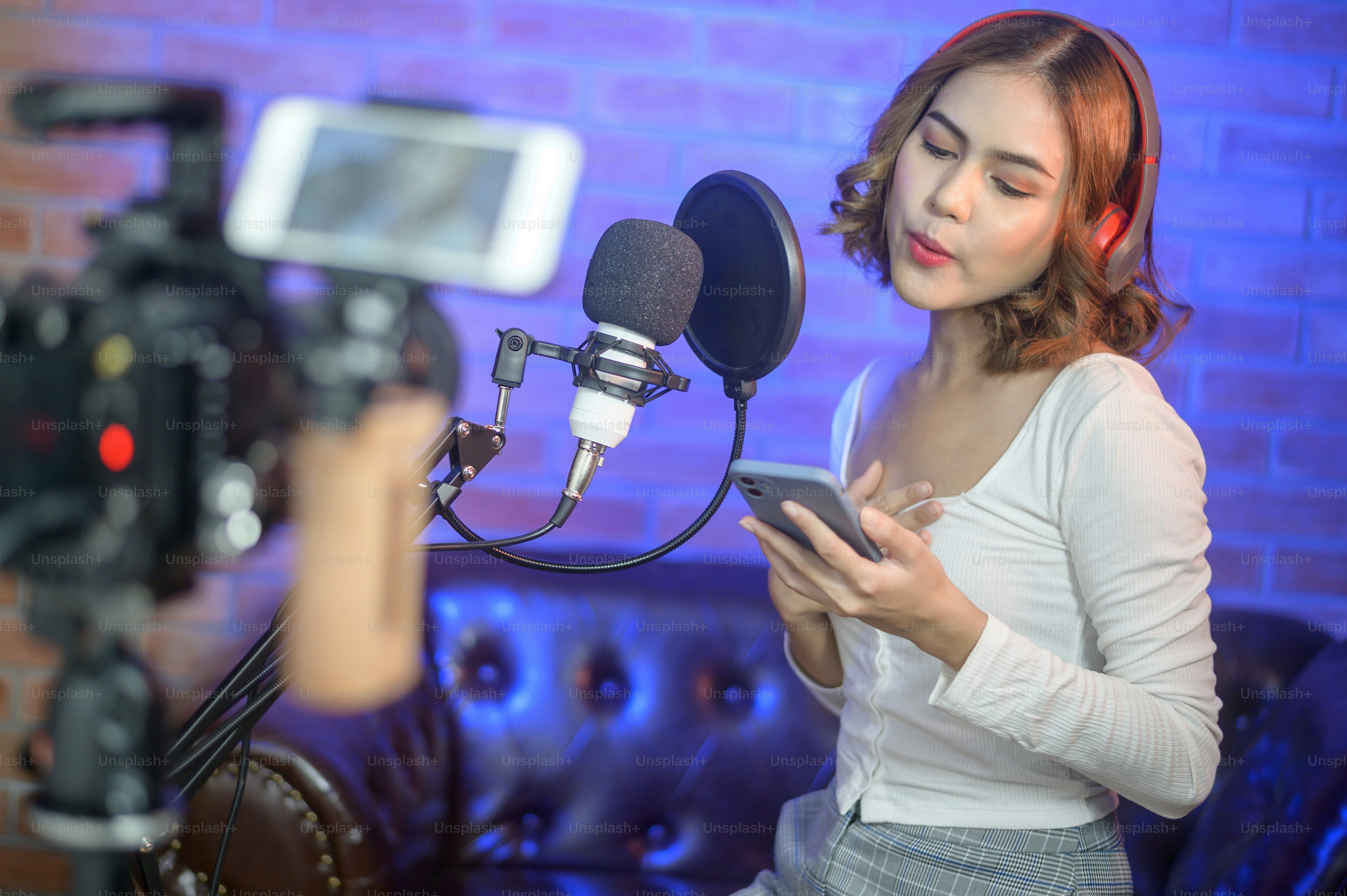 A young smiling female singer wearing headphones with a microphone ...