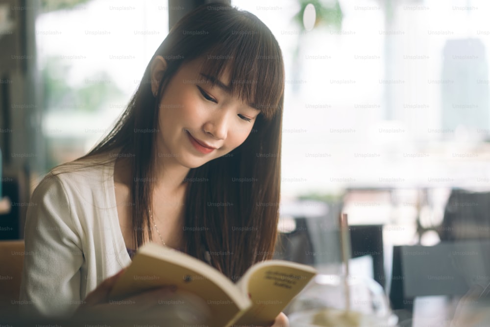 Asian teenager college student woman study and reading book at cafe. University people city lifestyle at outside from home on day concept.