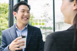 à¹Happy Asian business people colleagues talking in the office with cups of coffee