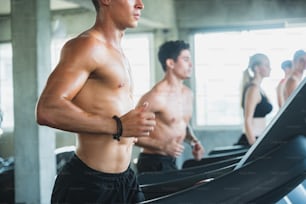 Gruppe von sportlichen Sportarten Laufen auf einem Laufband im Fitnessclub für Wellness-Gesundheit. Menschen im Fitnessstudio, um Muskeln und Körperkraft aufzubauen. Übungstrainingskonzept.