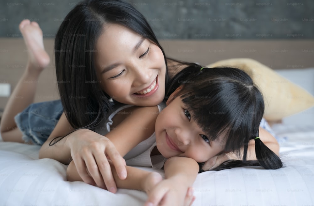Asiatische Mutter und Tochter lächeln und schauen in die Kamera. Happy love family Konzept