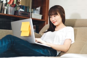 Studentin Mädchen lernen online bleiben zu Hause für soziale Distanzierung und neues normales Konzept. Glückliches Lächeln asiatische Teenager-Frau mit digitaler Konferenz über Internet mit Laptop im Wohnzimmer.