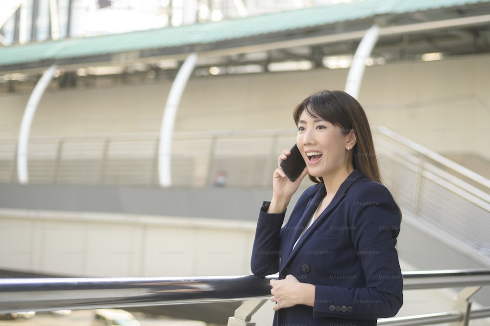 Bella giovane donna d'affari asiatica sta usando lo smartphone nella città moderna
