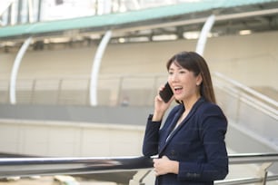 beautiful young asian business woman is using smartphone in modern city