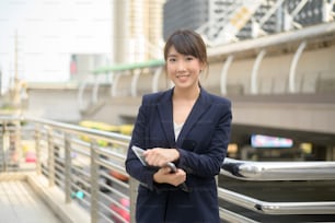 Retrato da bela mulher de negócios asiática jovem está trabalhando na cidade moderna