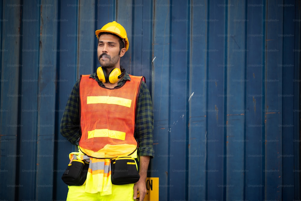 an employee foreman men worker smoking cigarette tobacco nicotine whlie take a break, relax work lifestyle concept, container site, outdoor smoking, men wearing safety vest, helmet and headphone, unhealthy concept
