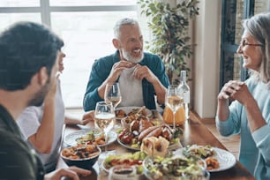 Smiling multi-generation family enjoying delicious dinner while sitting in the modern apartment