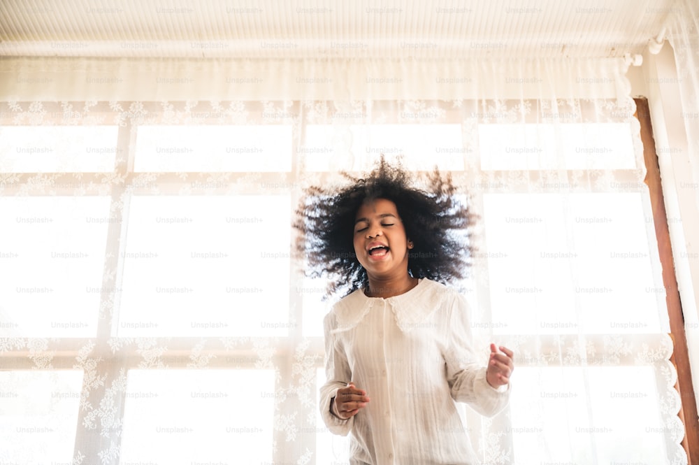 a little boy jumping on the bed, brother and sister sibling playing together, afro young boy in white background, cozy time at home. family relationship concept.