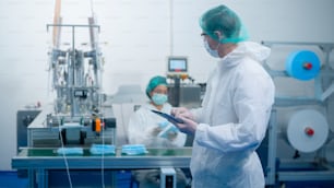 Workers producing surgical mask in modern factory, Covid-19 protection and medical concept.