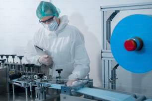 Workers producing surgical mask in modern factory, Covid-19 protection and medical concept.