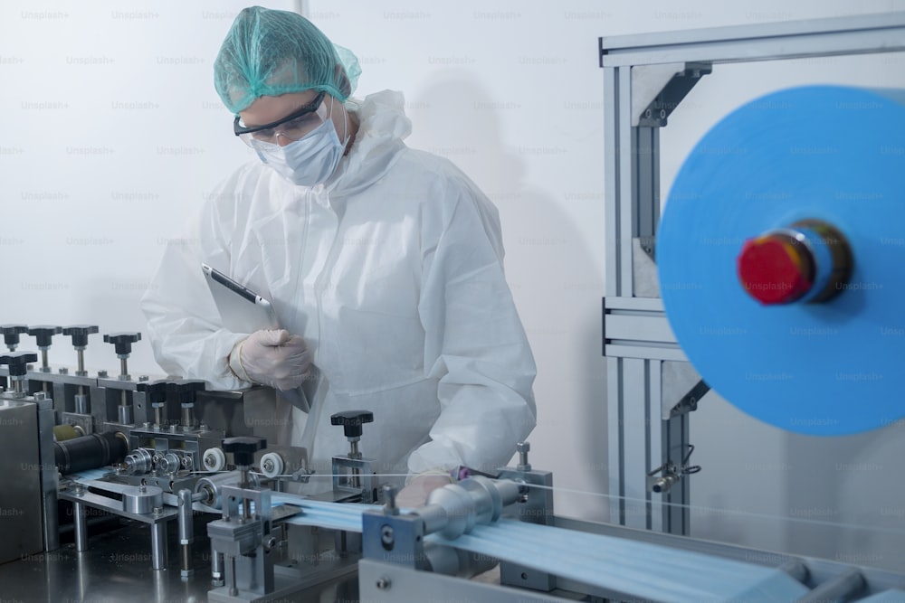 Trabajadores que producen mascarillas quirúrgicas en fábricas modernas, protección Covid-19 y concepto médico.