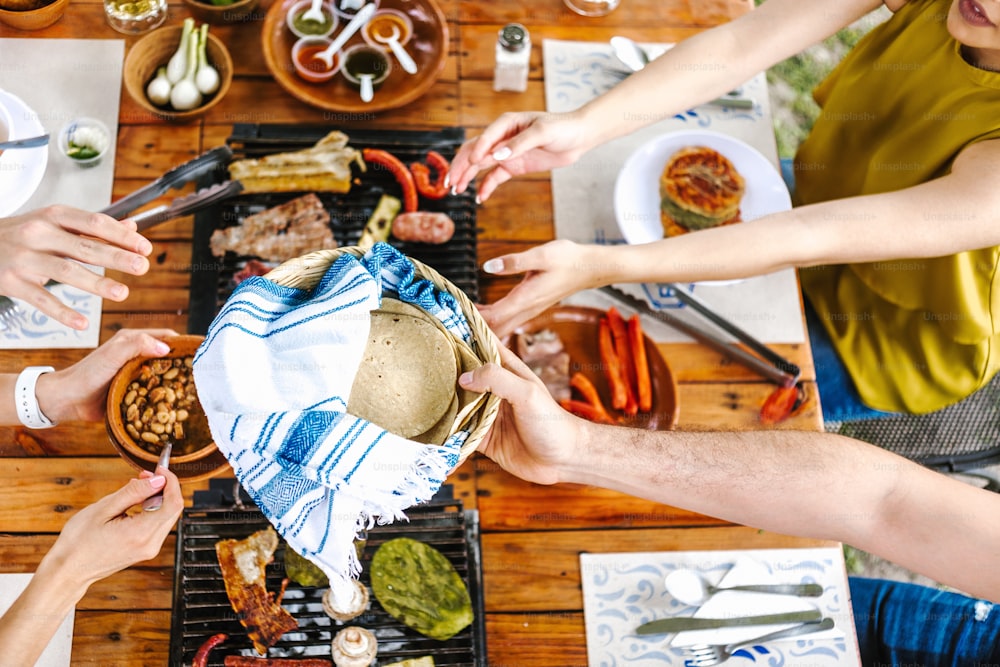 group of Friend eating Mexican Tacos and traditional food, snacks and peoples hands over table, top view. Mexican cuisine