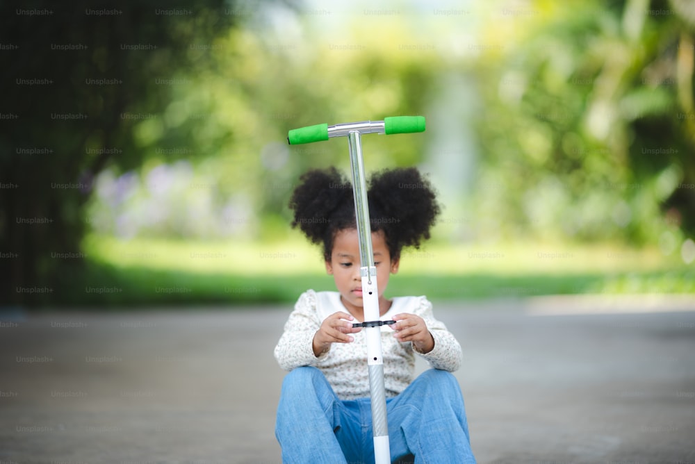 afro african kid riding on scooter, playing outdoor on a sunny day, outdoor activity concept, family concept. kid lifestyle. active sport kids.