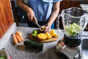 Latin Woman macht grünen Smoothie oder Detox-Saft in der Küche zu Hause in gesundem Ernährungskonzept in Mexiko
