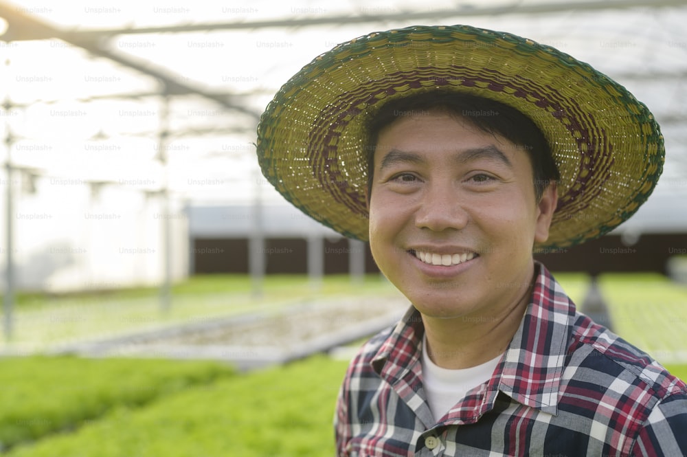 水耕栽培温室農場で働く幸せな男性農家、クリーンな食品と健康的な食事のコンセプト