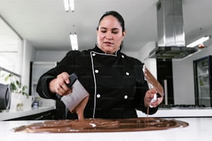 Lateinamerikanische Konditorin in schwarzer Uniform bei der Zubereitung köstlicher süßer Pralinen in der Küche in Mexiko Lateinamerika