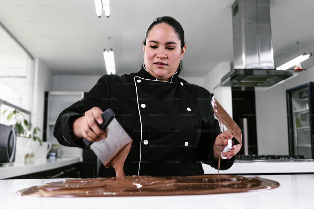 Chef pastelera latina con uniforme negro en proceso de preparación de deliciosos chocolates dulces en la cocina de México América Latina