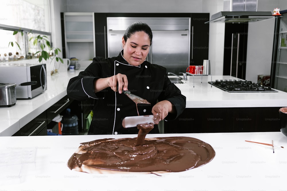 Chef pastelera latina con uniforme negro en proceso de preparación de deliciosos chocolates dulces en la cocina de México América Latina