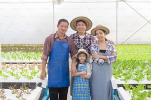 Una famiglia di agricoltori felice che lavora in una fattoria idroponica in serra, cibo pulito e concetto di alimentazione sana