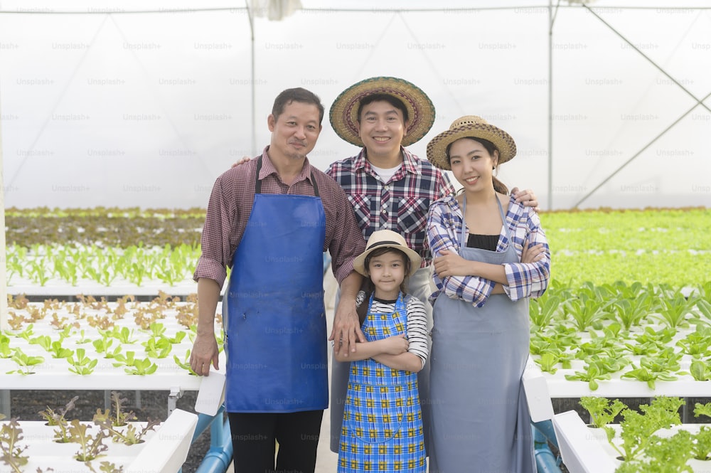 Una famiglia di agricoltori felice che lavora in una fattoria idroponica in serra, cibo pulito e concetto di alimentazione sana