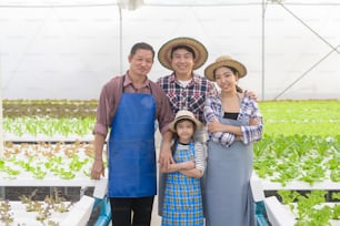 A happy farmer family working in hydroponic greenhouse farm, clean food and healthy eating concept