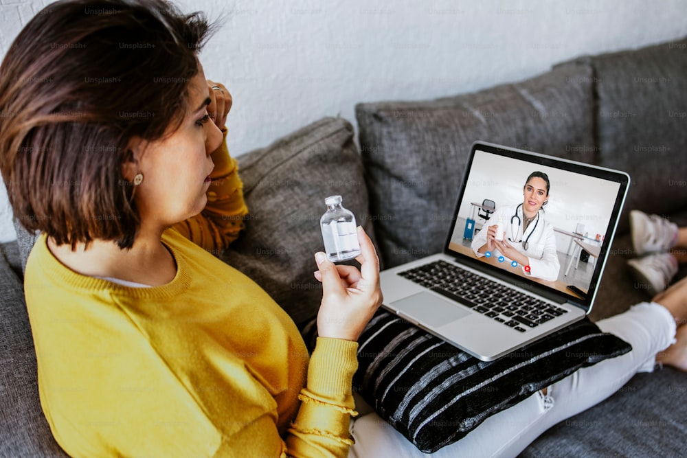Latin woman patient sit on couch at home have video call with female doctor online in Latin America