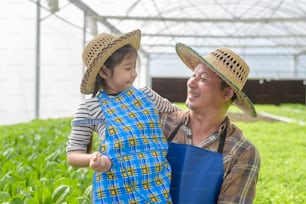 Happy farmer grandfather and little girl working in hydroponic greenhouse farm, clean food and healthy eating concept