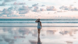 젊은 성인 관광 아시아 여성의 뒷모습은 아름다운 극적인 일몰 하늘과 함께 해변 모래 위에서 휴식을 취합니다. 안다만 바다의 야외 국내 여행. 푸켓, 태국.