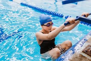 hispanic teenager girl swimmer athlete wearing cap and goggles in a swimming training at the Pool in Mexico Latin America